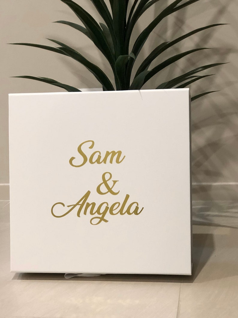 May include: White gift box with the names Sam & Angela written in gold lettering.