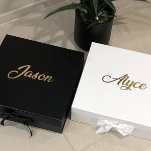 May include: Two personalized gift boxes, one black with the name "Jason" in gold lettering and one white with the name "Alyce" in gold lettering.