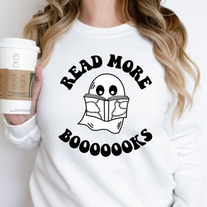 May include: White sweatshirt with a black graphic of a ghost reading a book with the text "Read More Booooks".