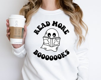 May include: White sweatshirt with a black graphic of a ghost reading a book with the text "Read More Booooks".
