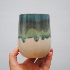 以下が含まれることがあります： 白い底に青、緑、グレーの釉薬が垂れ下がったセラミックマグカップ