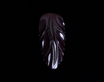 May include: A dark purple carved plastic brooch in the shape of a leaf.