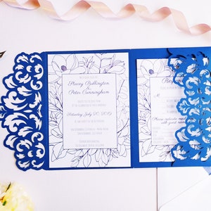 May include: Blue wedding invitation with a white floral design and a laser cut design on the front. The text on the invitation reads "Stacey Bullington & Peter Cunningham". The invitation is for a wedding on Saturday, July 20, 2019.