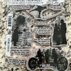 May include: A set of clear rubber stamps with black ink designs. The stamps feature various quotes and images, including a person walking on a tightrope, a car, and a person with a hat. The text on the stamps includes quotes such as "the greater the artist, the greater the doubt" and "leap and the net will appear".