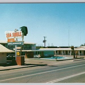 May include: Vintage postcard featuring the Sea Shell Motel with a retro sign. The motel has a pool and is set against a clear blue sky. The sign reads "Sea Shell Motel" in red and white.