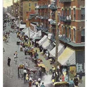 Op de afbeelding: Vintage ansichtkaart van Hester Street in New York, gedateerd 21 november '45. De afbeelding toont een drukke straat met verkopers, shoppers en bakstenen gebouwen. De ansichtkaart heeft handgeschreven tekst en is een souvenir.