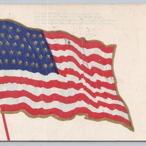 May include: Vintage postcard featuring a waving American flag with red and white stripes and a blue field of stars. The flag is outlined in gold, with gold embellishments at the top. The postcard has text on the right side.