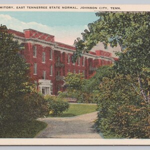 May include: Vintage postcard featuring the Girls' Dormitory at East Tennessee State Normal in Johnson City, Tenn. The brick building is framed by lush greenery and a winding path. The text at the top reads "GIRLS' DORMITORY, EAST TENNESSEE STATE NORMAL, JOHNSON CITY, TENN."