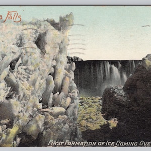 Op de afbeelding: Vintage ansichtkaart met de Niagara Falls. De afbeelding toont de watervallen met ijsformaties op de voorgrond en de tekst "Niagara Falls" en "First Formation of Ice Coming Over Falls". De ansichtkaart heeft een vintage esthetiek.