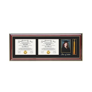 May include: A rectangular mahogany-finished frame with a black mat containing two white diplomas with gold seals, a portrait of a graduate in a cap and gown, a gold tassel, and the text Gradframes by 3art and Class of 2026 printed on the mat.