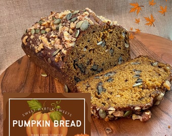 May include: A loaf of pumpkin bread with walnuts and pumpkin seeds on top. The bread is sliced and the inside is visible. The bread is on a wooden cutting board. The bread is labeled "Sweet Myrtle Sweets Pumpkin Bread Made from Scratch with Walnuts Pumpkin Spice".