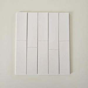 May include: Six white rectangular pieces of paper, arranged in a row, with a slight gap between each piece.