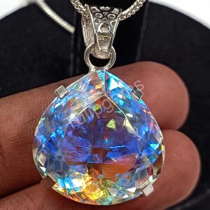 May include: A pear-shaped pendant with a large, faceted, iridescent gemstone. The gem displays a spectrum of colors, including blues, greens, and yellows. The pendant is suspended from a silver chain and has a silver bail.