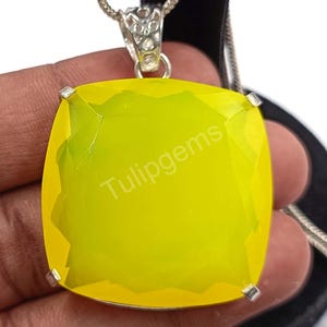 May include: A square, yellow pendant with the text "Tulipgems" is suspended from a silver chain. The pendant has a faceted surface and is held in place by four silver prongs. The chain is a delicate, silver snake chain.