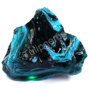 May include: A large, irregularly shaped piece of glass with a striking combination of teal and black colors. The glass has a glossy, reflective surface with swirling patterns. The text "Tutipgems" is visible on the surface.