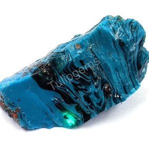 May include: A vibrant, irregularly shaped, blue-green gemstone with dark, swirling patterns. The surface has a glossy sheen, and the stone appears to be translucent in areas. The word "Tulipgems" is visible on the surface.