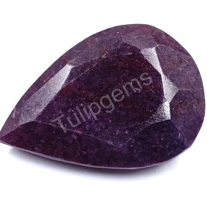 Puede incluir: Una gema facetada en forma de pera, de color púrpura intenso. La superficie pulida refleja la luz. El texto "Tulipgems" es visible en la superficie de la gema.