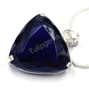 May include: A triangular, faceted, deep blue gemstone pendant with a silver chain. The gemstone is set in a silver bezel and has the text "Tulipgems" printed on it. The pendant is displayed on a white background.