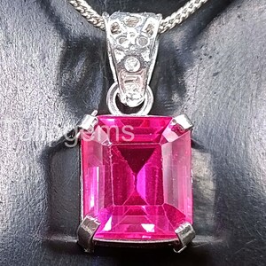 May include: A silver pendant necklace with a large, rectangular, faceted, hot pink gemstone. The gemstone is set in a silver bezel and hangs from a silver chain. The word "gems" is partially visible on the image.