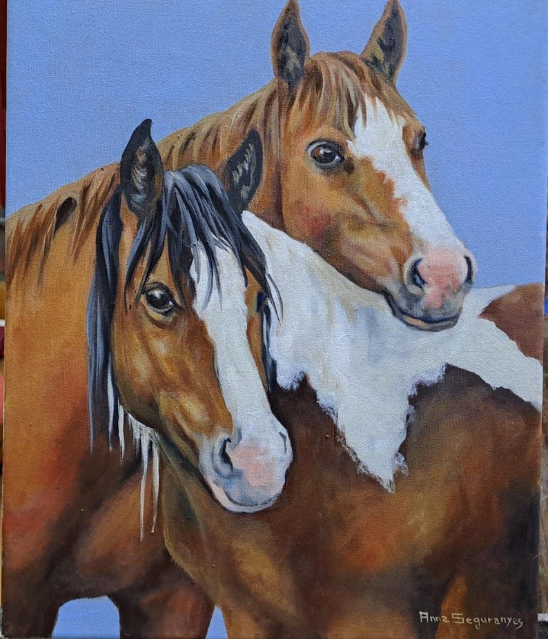 May include: An oil painting of two horses, one with a black mane and the other with a brown mane. Both horses have white markings on their faces and chests. The background is a light blue. The painting is signed by the artist, Ama Seguranyes.