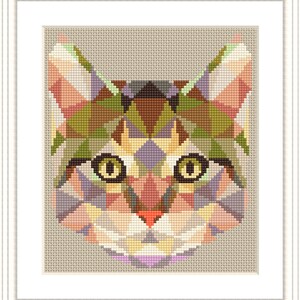 May include: A framed cross-stitch of a cat's face, featuring a geometric design. The cat's face is composed of various colored triangles, including shades of pink, green, brown, and purple. The eyes are yellow with black pupils, and the nose is red.