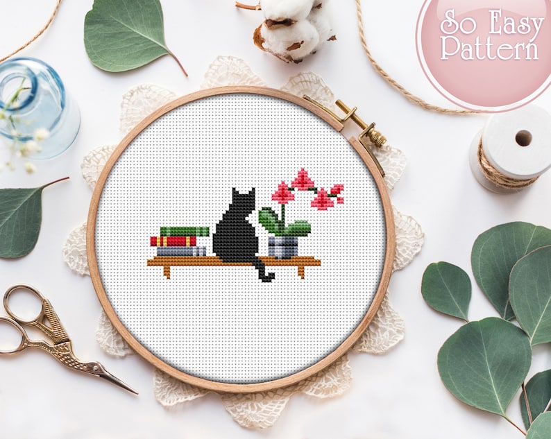 May include: A black cat sitting on a shelf with a stack of books and a potted pink orchid plant. The shelf is made of wood and has a white background.