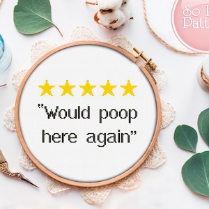Puede incluir: Un aro de bordado blanco con un diseño de punto de cruz que dice "Would poop here again" con cinco estrellas amarillas sobre el texto.