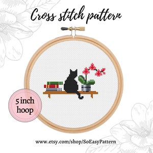 May include: Cross stitch pattern of a black cat sitting on a shelf with a stack of books and a potted orchid plant. The pattern is designed for a 5 inch hoop.