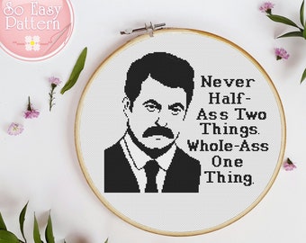 May include: Black and white cross-stitch pattern featuring a cartoon portrait of Ron Swanson from the TV show Parks and Recreation. The quote "Never Half-Ass Two Things. Whole-Ass One Thing." is stitched below the portrait.