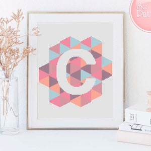 May include: A framed cross-stitch pattern of the letter C in a geometric design with pink, orange, blue, and brown triangles. The title "So Easy Pattern" is in a pink circle in the upper right corner of the image.