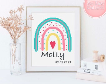 May include: Cross stitch pattern featuring a rainbow with a heart in the centre and the name "Molly" and the date "02.11.2021" below.