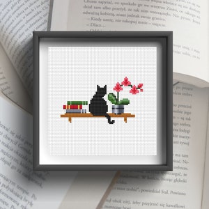 May include: A black cat sitting on a shelf with a stack of books and a potted pink orchid plant. The cat is looking at the orchid.