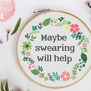 May include: A white embroidery hoop with a floral wreath design and the text "Maybe swearing will help".