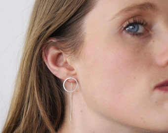 May include: Silver earrings with a thin, long rod and a small circle at the top.