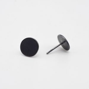 Op de afbeelding: Een paar zwarte ronde oorbel studs. De oorbellen zijn gemaakt van metaal en hebben een eenvoudig, minimalistisch ontwerp.