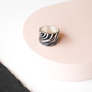 Può includere: Un anello largo in argento con un motivo a strisce zebrate in bianco e nero.