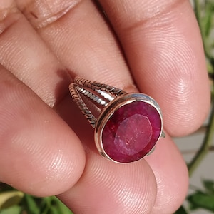 Op de afbeelding: Een zilveren ring met een rode ovale edelsteen. De ring heeft een gedraaide band.