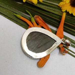 May include: A silver pendant with a teardrop-shaped labradorite gemstone. The pendant is set in a silver bezel and has a loop for attaching a chain.