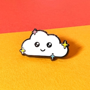 May include: A white enamel cloud pin with a smiling face and black outline. The pin features three colourful star accents and a black border. The pin is set against a yellow and red background.
