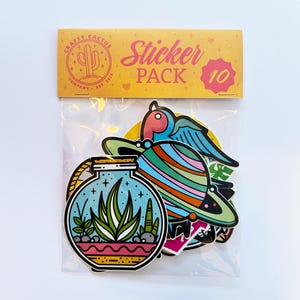 May include: A pack of 10 colourful stickers featuring various designs, including a potted plant, a planet, and a bird. The sticker pack is labelled "Crafty Cactus Company - Est. 2018" and "Sticker Pack 10".