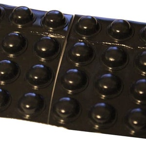 May include: A sheet of black adhesive-backed bumpers, designed to protect surfaces from scratches and dents. The bumpers are arranged in a grid pattern and are ready to be peeled and applied.
