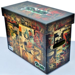 Puede incluir: Una caja de almacenamiento de cartón con temática de cómics de Spawn. La caja está cubierta de imágenes de los cómics de Spawn. La caja tiene una manija en el lateral y la palabra "Spawn" está impresa en la parte delantera.