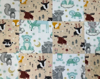 May include: A patchwork quilt with a woodland animal theme. The quilt is made of squares of fabric with different animal designs, including deer, moose, raccoons, squirrels, and bears. The fabric is in shades of brown, gray, white, and blue.