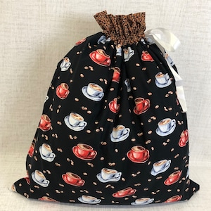 May include: A black drawstring bag with a white ribbon. The bag is decorated with a repeating pattern of coffee cups and coffee beans.