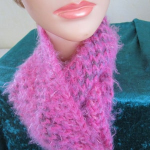 Könnte beinhalten: Ein flauschiger, gestrickter Halsschmuck in Rosa und Grau. Der Halsschmuck ist aus weichem, flauschigem Garn gefertigt und hat ein schlichtes, elegantes Design.