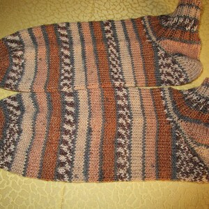 Könnte beinhalten: Ein Paar gestreifte Socken in Braun-, Rosa- und Grautönen. Die Socken sind mit einem strukturierten Muster gestrickt.