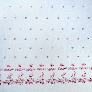 Può includere: Tessuto bianco con un motivo ripetuto di piccoli accenti floreali rosa. Un bordo di fiori di magnolia rosa più grandi e foglie adorna il bordo inferiore. Il tessuto ha una trama sottile.