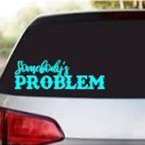 May include: A teal blue vinyl decal with the text "Somebody's PROBLEM" on a black car window.