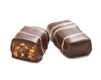 May include: Two chocolate candies, one broken open to reveal a filling of nuts and caramel. The candies are dark brown with light brown stripes.