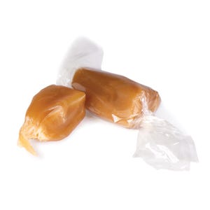 May include: Two pieces of caramel candy, one wrapped in clear plastic and the other unwrapped, both with a golden brown color.